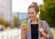 Younger woman smiling and looking at phone outside